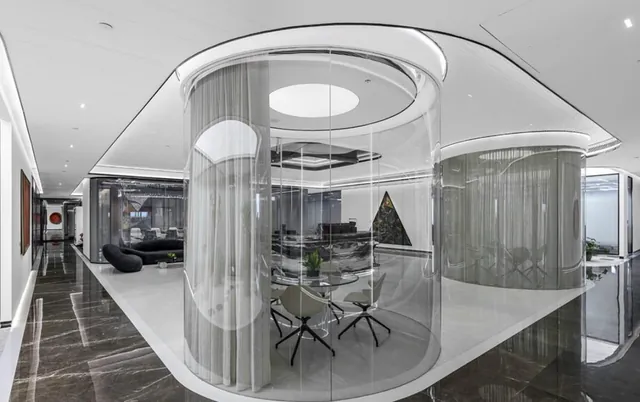 Circular glass and mesh meeting room in a monochrome workspace