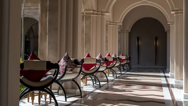 Sunlit arcade with arched colonnade and red-cushioned seating