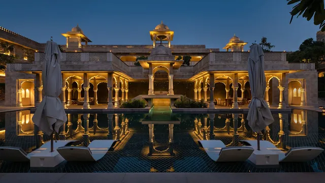 Heritage palace facade lit at night, reflected in the pool